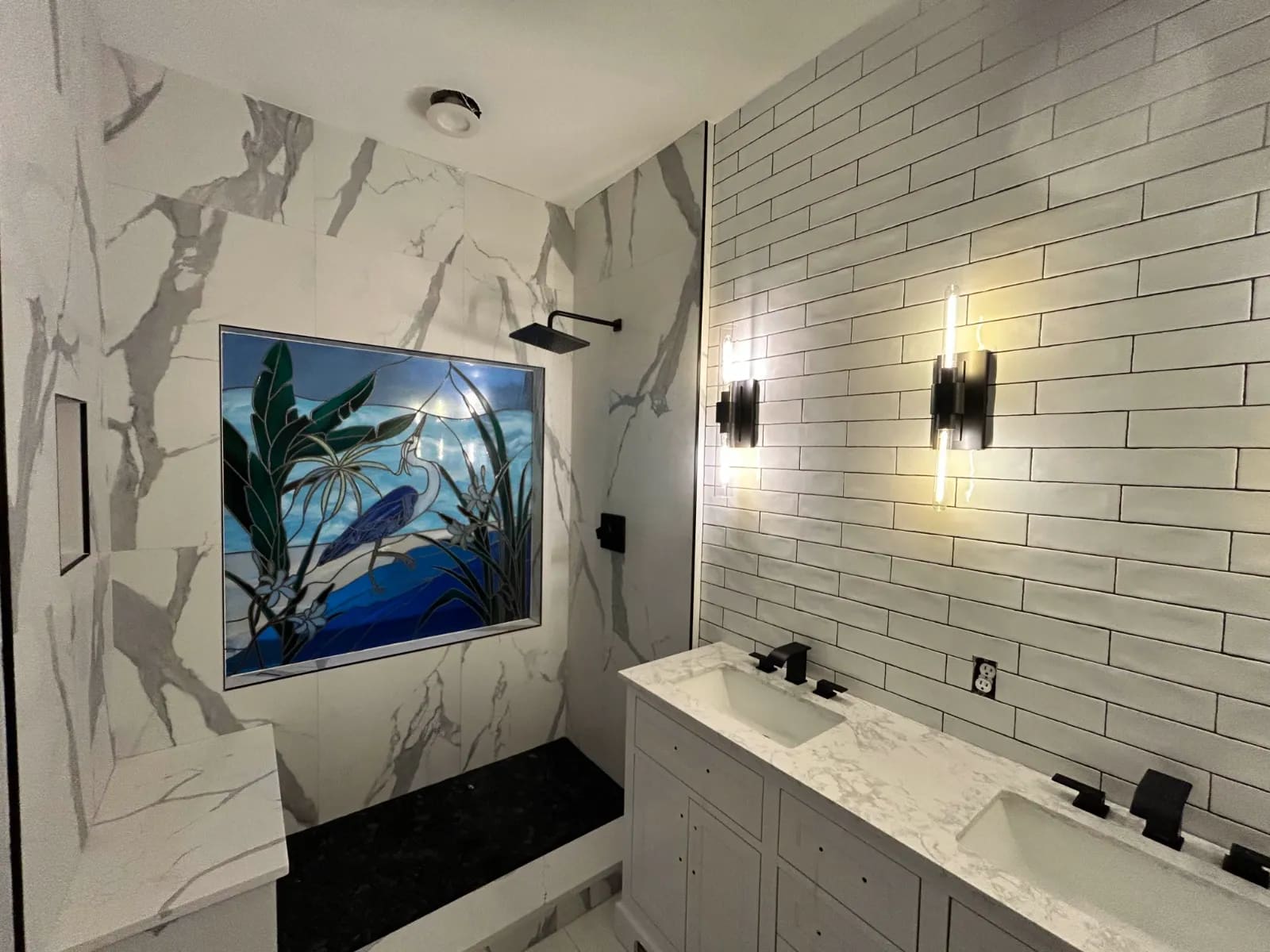 Bathroom renovation with large-format marble-look porcelain in the shower, a stained-glass window panel, matte black fixtures and a double vanity